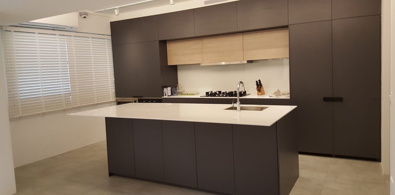 Charcoal cabinetry, white quartz island, earlier work by Aura Design & Co.